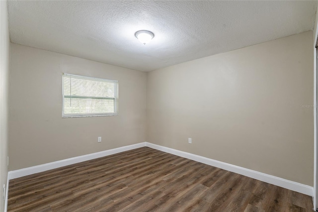 empty room with a textured ceiling and dark hardwood / wood-style flooring