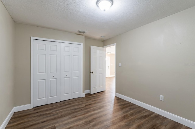 unfurnished bedroom featuring a closet, dark wood-type flooring, and a textured ceiling