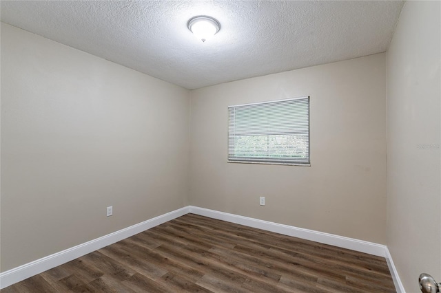 empty room with dark wood-type flooring and a textured ceiling