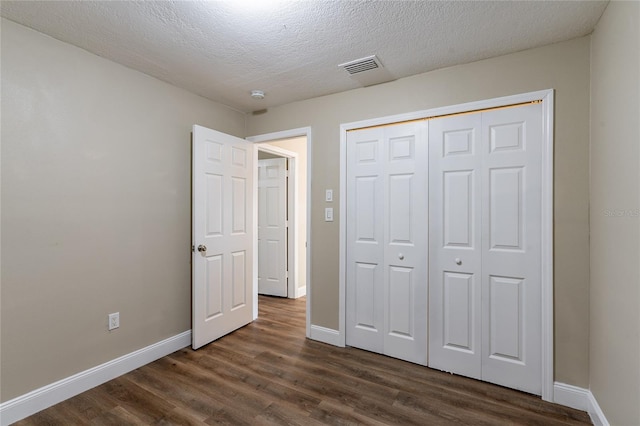 unfurnished bedroom featuring a closet, dark wood-type flooring, and a textured ceiling