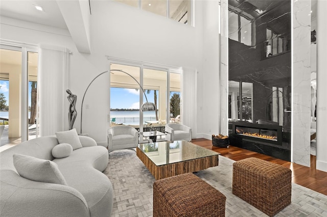 living room with beam ceiling, wood-type flooring, a water view, and a fireplace