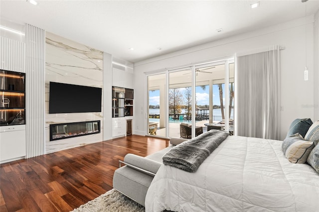 bedroom with wood-type flooring, access to exterior, and a fireplace