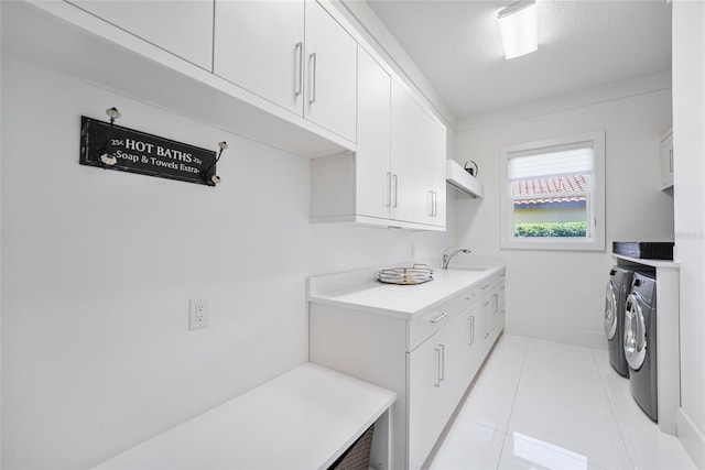 clothes washing area with sink, cabinets, light tile patterned floors, independent washer and dryer, and a textured ceiling