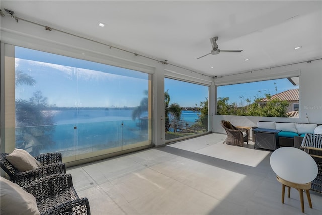 sunroom featuring plenty of natural light, ceiling fan, and a water view