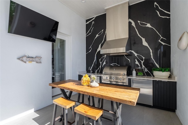 kitchen with fridge, a kitchen breakfast bar, and wall chimney range hood