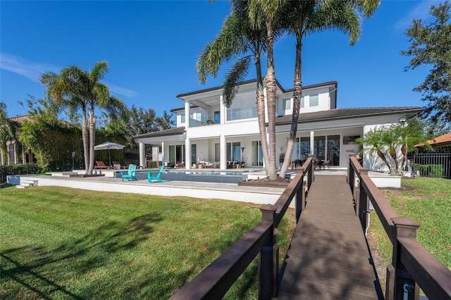 rear view of house with a fenced in pool, a patio area, and a lawn