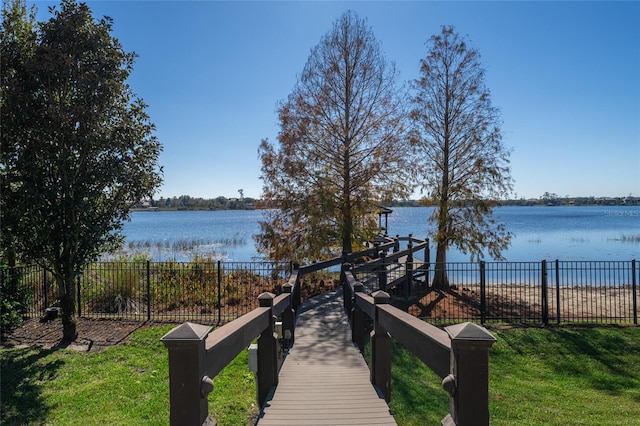 view of dock with a water view and a yard