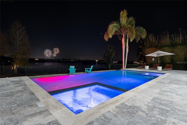 pool at twilight featuring a patio and an in ground hot tub