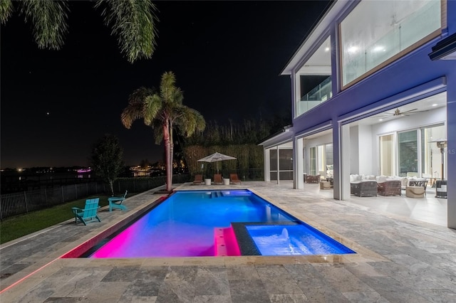 pool at night with outdoor lounge area, a patio, an in ground hot tub, ceiling fan, and a sunroom