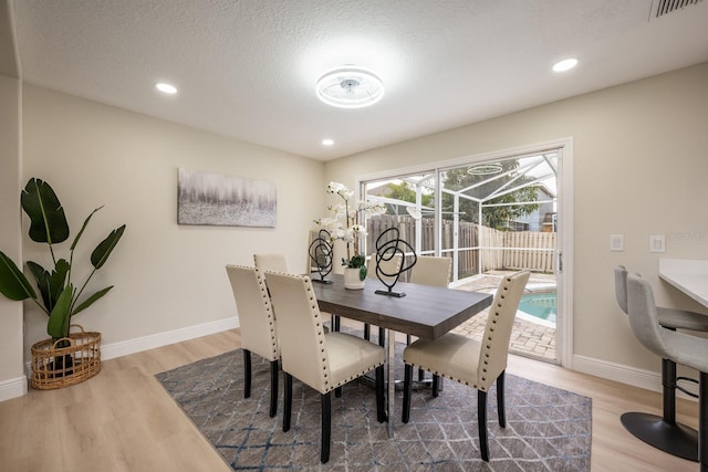 dining area with hardwood / wood-style floors and a textured ceiling