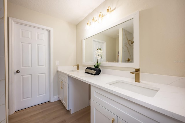 bathroom with a textured ceiling, wood-type flooring, and vanity