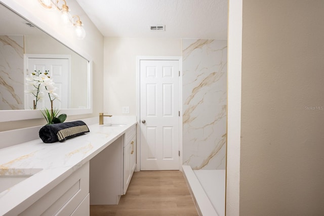 bathroom featuring a textured ceiling, a shower, wood-type flooring, and vanity