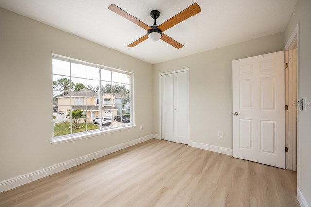 unfurnished bedroom featuring ceiling fan, a closet, and light wood-type flooring