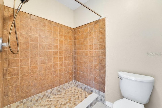 bathroom with a tile shower and toilet