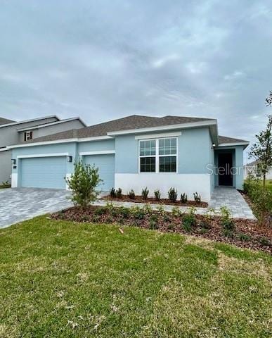 single story home with a garage and a front lawn