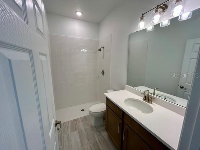 bathroom featuring tiled shower, vanity, and toilet