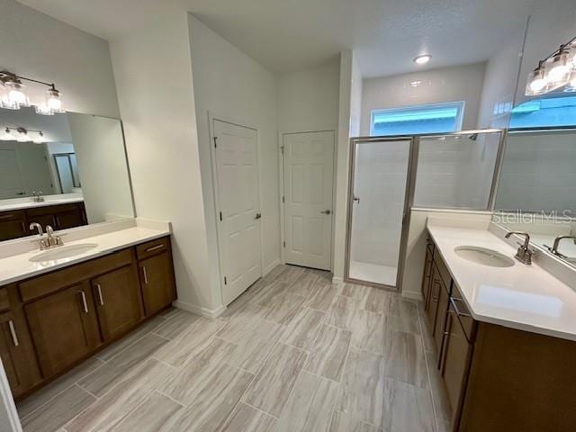 bathroom featuring a shower with shower door and vanity