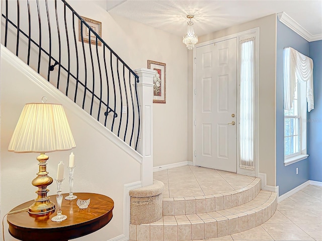 tiled entryway featuring ornamental molding and a chandelier