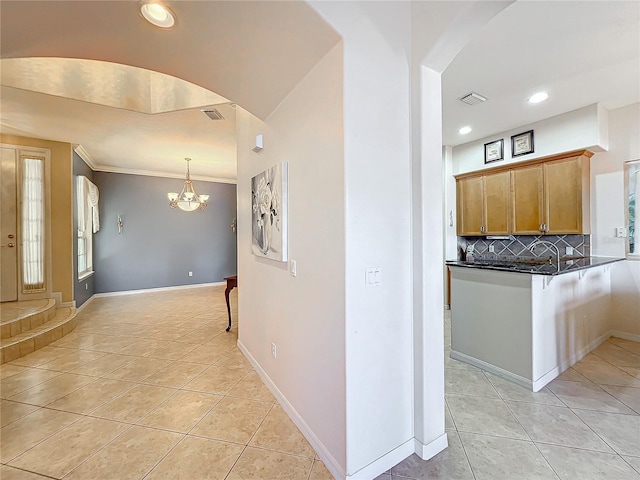 kitchen featuring kitchen peninsula, backsplash, light tile patterned floors, and an inviting chandelier