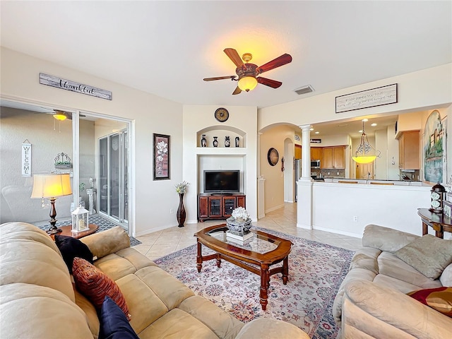 tiled living room featuring built in shelves, ornate columns, and ceiling fan