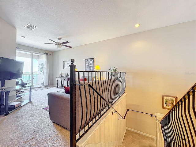 living room with a textured ceiling, light colored carpet, and ceiling fan