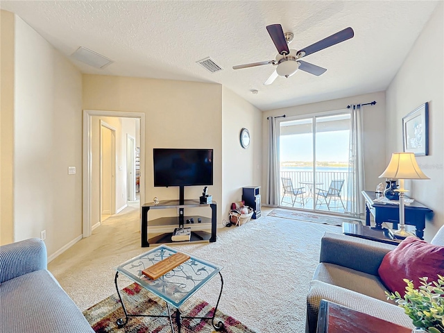 carpeted living room featuring ceiling fan and a textured ceiling