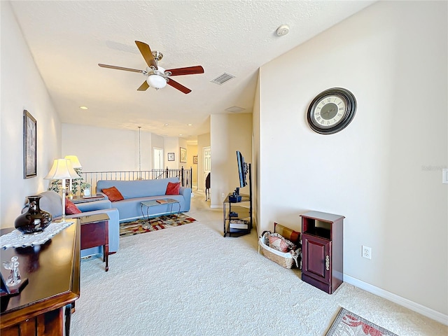 carpeted living room with ceiling fan and a textured ceiling