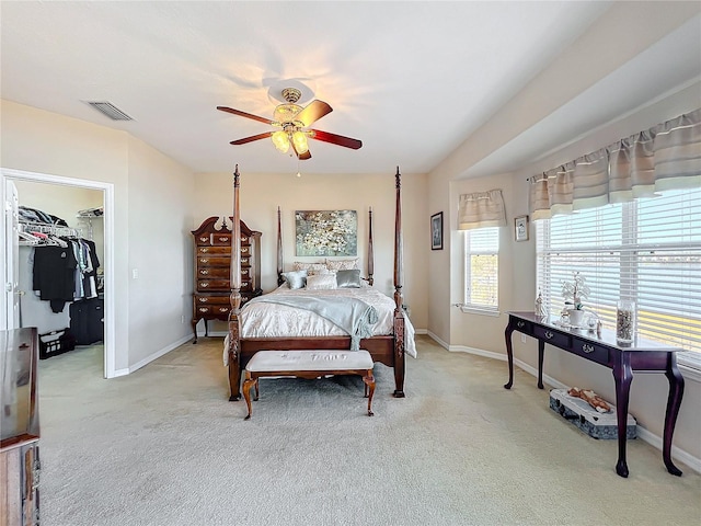 bedroom featuring a spacious closet, a closet, ceiling fan, and light colored carpet