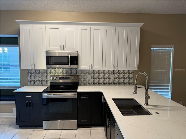 kitchen with white cabinets, light stone counters, sink, and stainless steel appliances