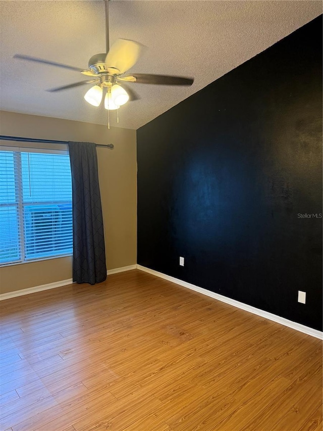 spare room featuring light wood-type flooring, a textured ceiling, and ceiling fan