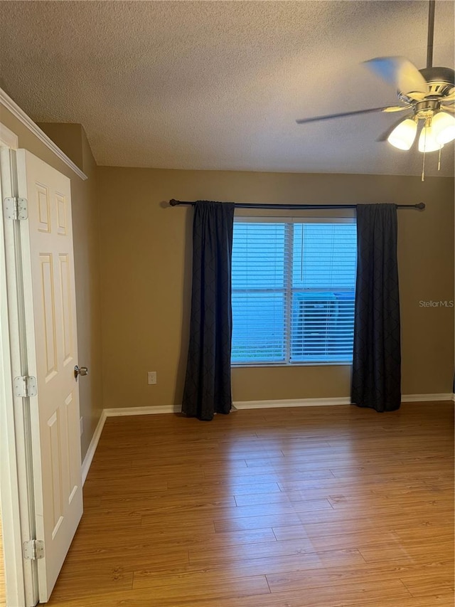 empty room featuring a textured ceiling, light hardwood / wood-style floors, and ceiling fan