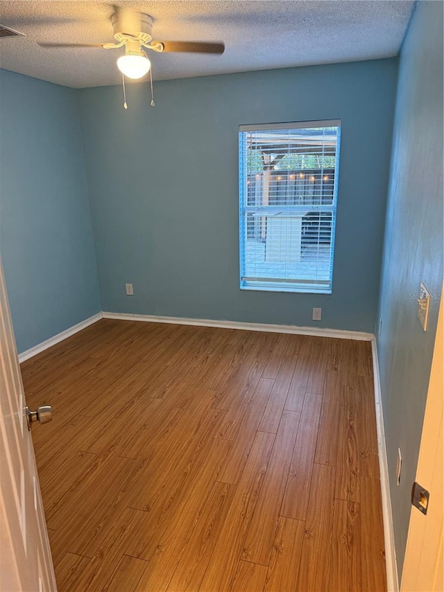 unfurnished room featuring hardwood / wood-style flooring, ceiling fan, and a textured ceiling