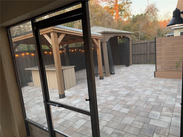 patio terrace at dusk featuring a gazebo and a jacuzzi