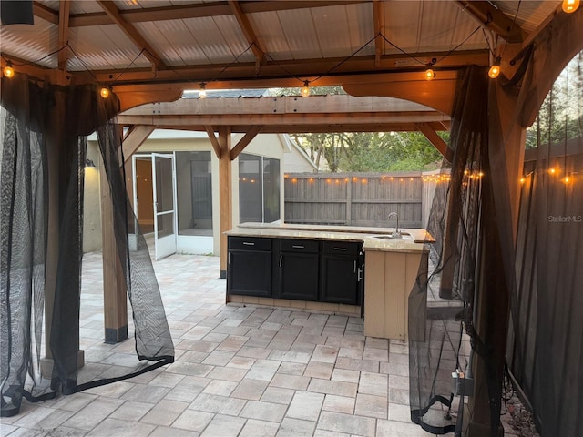 view of patio / terrace featuring a gazebo, a sunroom, and an outdoor wet bar