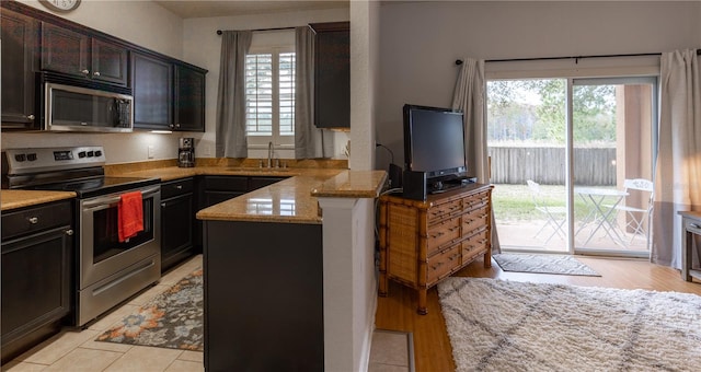 kitchen featuring sink, stainless steel appliances, light stone countertops, and plenty of natural light