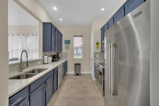 kitchen with blue cabinetry, sink, decorative backsplash, light tile patterned flooring, and appliances with stainless steel finishes