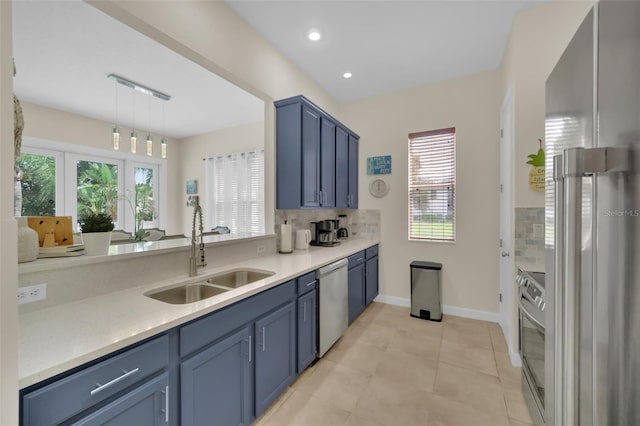 kitchen featuring blue cabinetry, sink, backsplash, decorative light fixtures, and appliances with stainless steel finishes