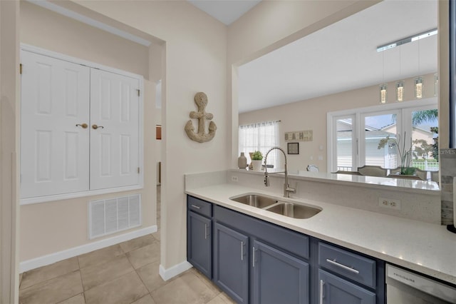 kitchen with blue cabinetry, light tile patterned floors, stainless steel dishwasher, and sink