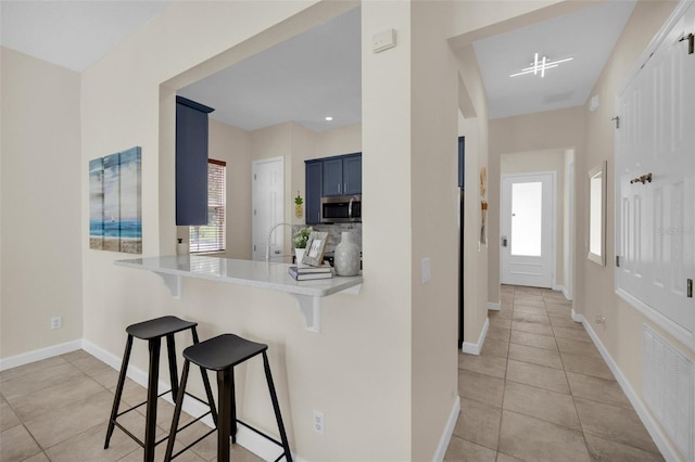 kitchen with a kitchen breakfast bar, blue cabinets, kitchen peninsula, and light tile patterned floors