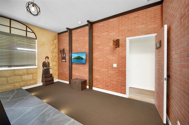 unfurnished living room featuring brick wall