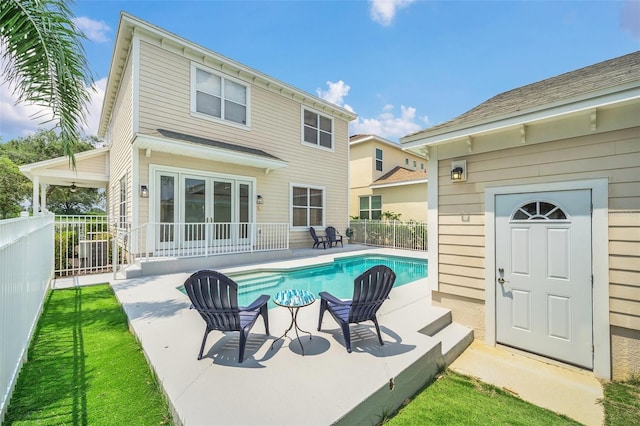 rear view of property with a fenced in pool and a patio