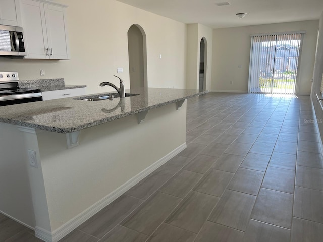 kitchen with stainless steel appliances, a breakfast bar area, white cabinets, and sink