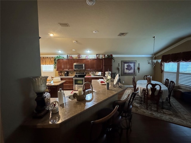 dining room featuring sink, a chandelier, vaulted ceiling, and ornamental molding