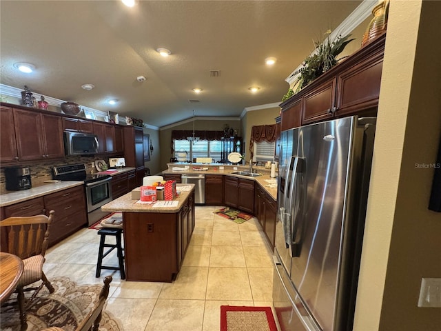 kitchen featuring vaulted ceiling, stainless steel appliances, a center island, ornamental molding, and tasteful backsplash