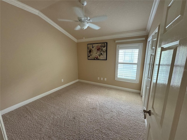 carpeted empty room with ceiling fan, a textured ceiling, baseboards, and crown molding