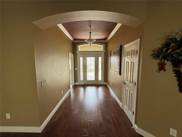 entryway with arched walkways, a textured ceiling, dark wood-style flooring, baseboards, and crown molding