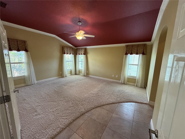 tiled spare room featuring carpet floors, a wealth of natural light, crown molding, and lofted ceiling