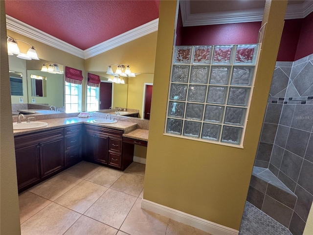 bathroom with a textured ceiling, ornamental molding, tile patterned flooring, and a sink