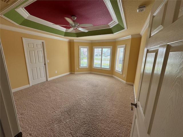 interior space with a ceiling fan, baseboards, a tray ceiling, and crown molding