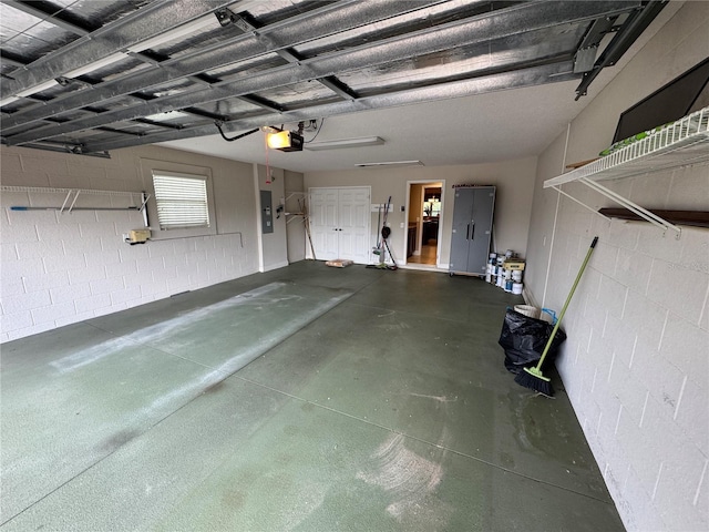 garage featuring a garage door opener, concrete block wall, and electric panel